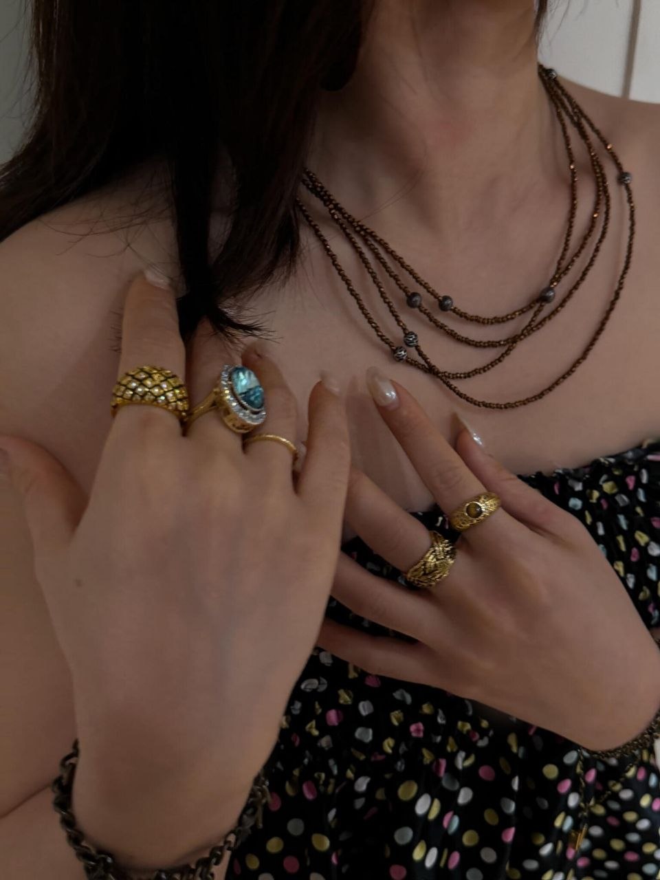 Side view of multiple layered bronze chain necklaces with small beaded accents positioned at varying lengths on the neck