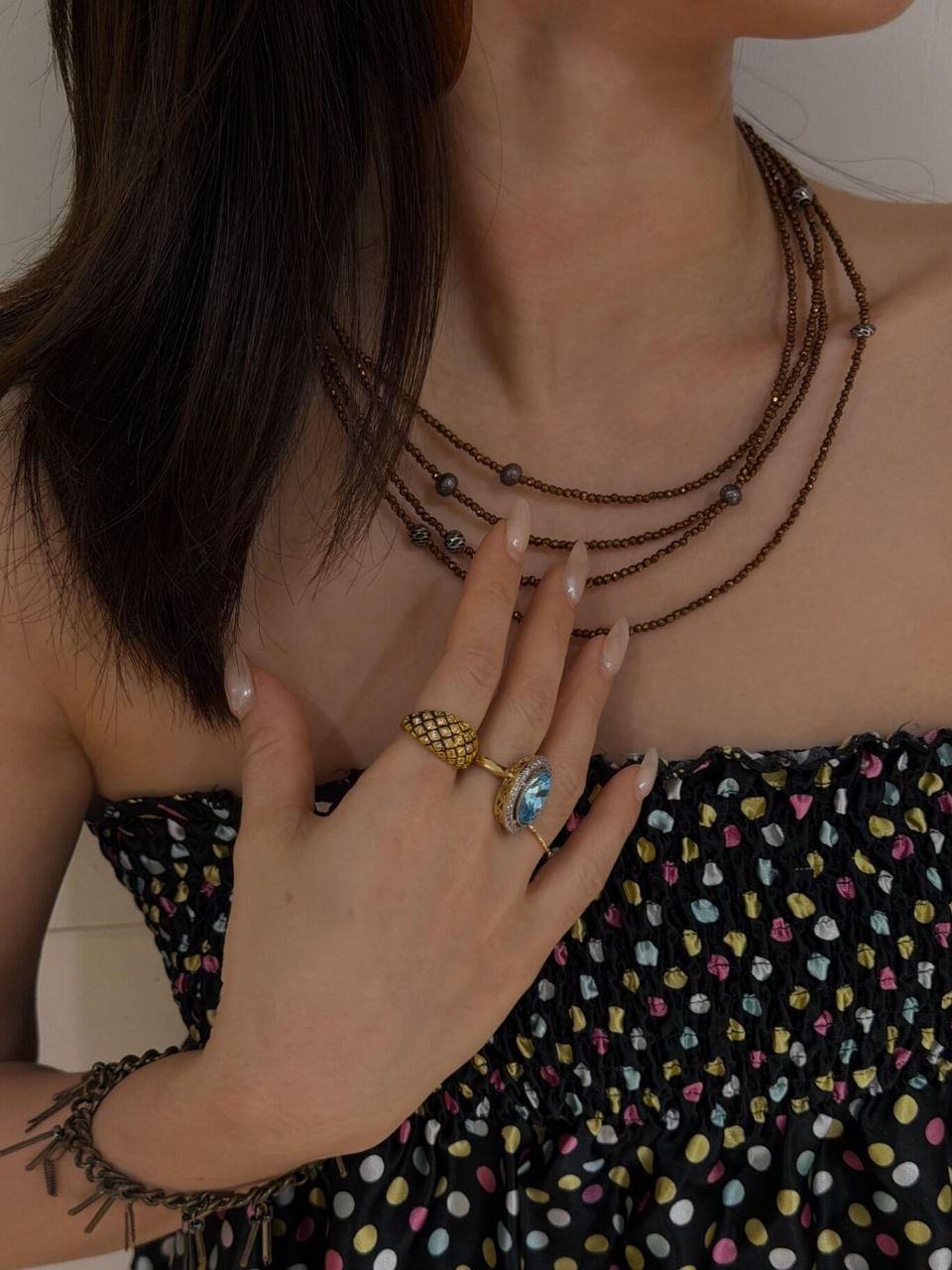 Side profile showing complete jewelry layering with stacked rings, layered necklaces at multiple levels, and overall silhouette