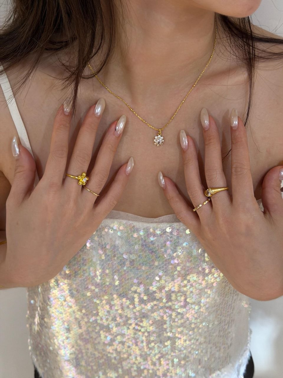 Close-up of gold pendant necklace worn at collarbone, showing delicate chain and statement pendant against bare skin